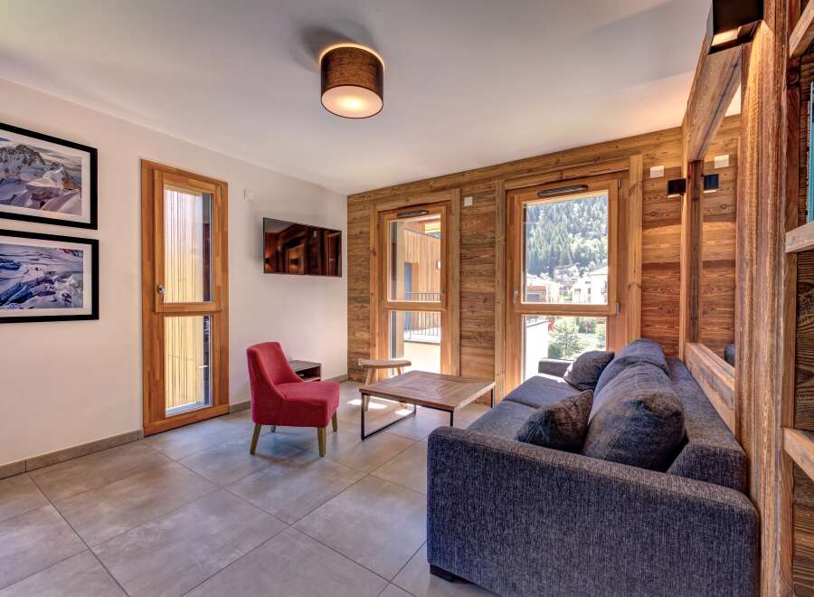 Experience mountain living in this charming living room featuring a cozy grey sofa and a vibrant red accent chair.