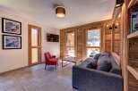 Experience mountain living in this charming living room featuring a cozy grey sofa and a vibrant red accent chair.