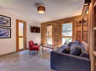 Experience mountain living in this charming living room featuring a cozy grey sofa and a vibrant red accent chair.