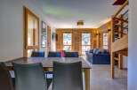 Experience mountain living in this beautifully appointed apartment, featuring a spacious dining area with sleek leather chairs and a modern table.