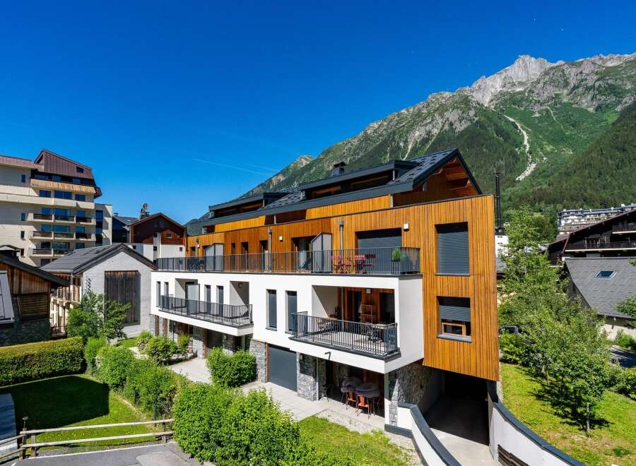 Experience modern alpine living in this stunning property featuring a striking wood-paneled facade and expansive balconies offering breathtaking mountain views.