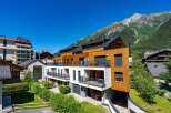 Experience modern alpine living in this stunning property featuring a striking wood-paneled facade and expansive balconies offering breathtaking mountain views.