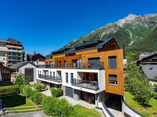 Experience modern alpine living in this stunning property featuring a striking wood-paneled facade and expansive balconies offering breathtaking mountain views.