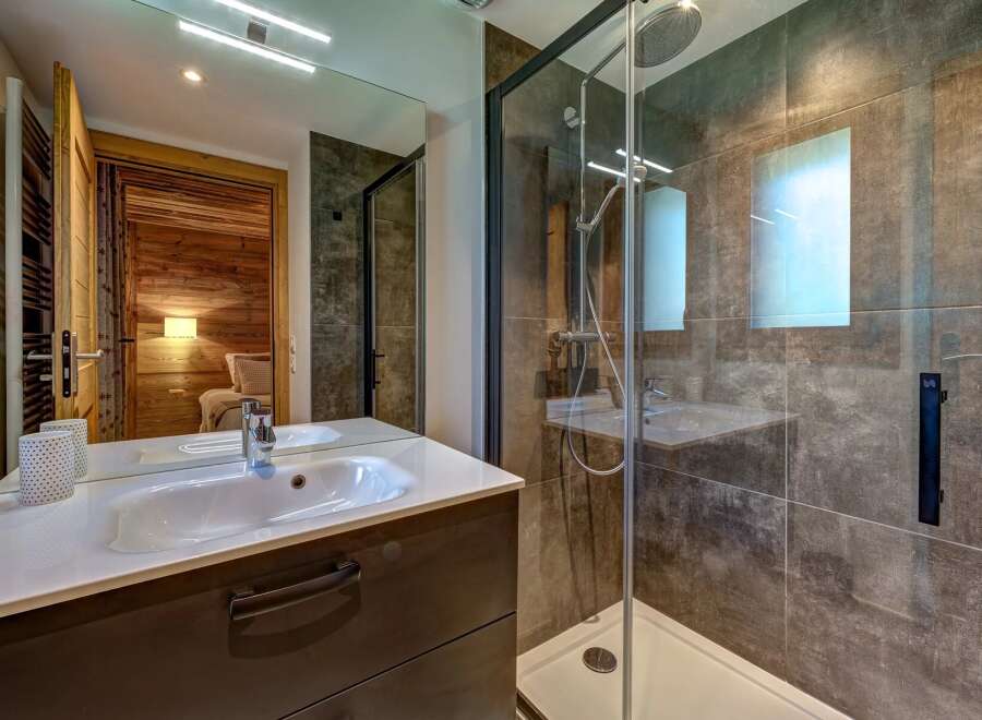 Experience modern comfort in this stylish bathroom, featuring a sleek vanity with a pristine white sink and a spacious glass-enclosed shower with a rainfall showerhead.
