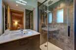 Experience modern comfort in this stylish bathroom, featuring a sleek vanity with a pristine white sink and a spacious glass-enclosed shower with a rainfall showerhead.