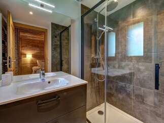 Experience modern comfort in this stylish bathroom, featuring a sleek vanity with a pristine white sink and a spacious glass-enclosed shower with a rainfall showerhead.