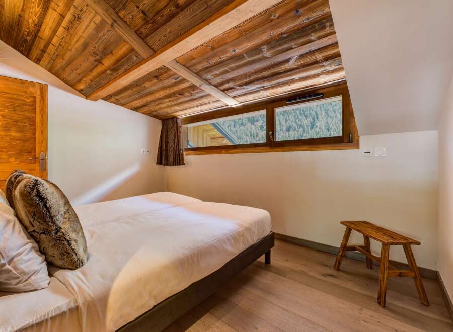 Experience rustic charm in this cozy bedroom featuring a beautifully paneled wooden ceiling and walls.