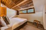 Experience rustic charm in this cozy bedroom featuring a beautifully paneled wooden ceiling and walls.