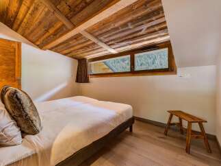 Experience rustic charm in this cozy bedroom featuring a beautifully paneled wooden ceiling and walls.