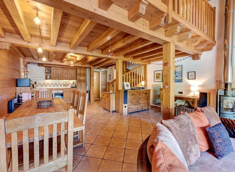 Experience rustic charm in this spacious mountain chalet, featuring a warm wooden interior with exposed beams and a cozy dining area.