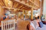 Experience rustic charm in this spacious mountain chalet, featuring a warm wooden interior with exposed beams and a cozy dining area.