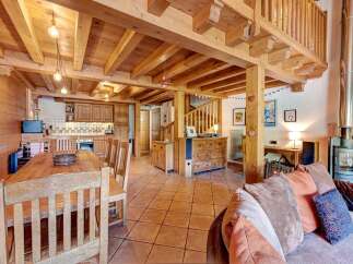 Experience rustic charm in this spacious mountain chalet, featuring a warm wooden interior with exposed beams and a cozy dining area.