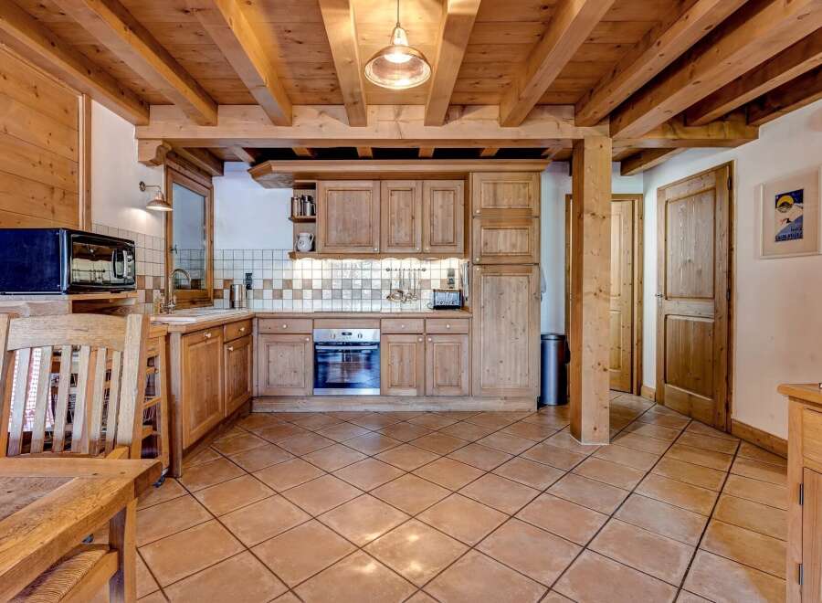Experience rustic charm in this beautifully appointed kitchen, featuring warm wooden cabinetry and exposed beams that create a cozy, inviting atmosphere.