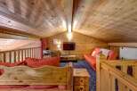 Experience cozy living in this charming wooden loft, featuring a comfortable red sofa and a rustic wooden bench with heart details.