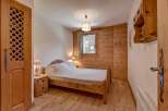Experience rustic charm in this cozy bedroom featuring warm wooden walls and flooring.