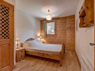 Experience rustic charm in this cozy bedroom featuring warm wooden walls and flooring.
