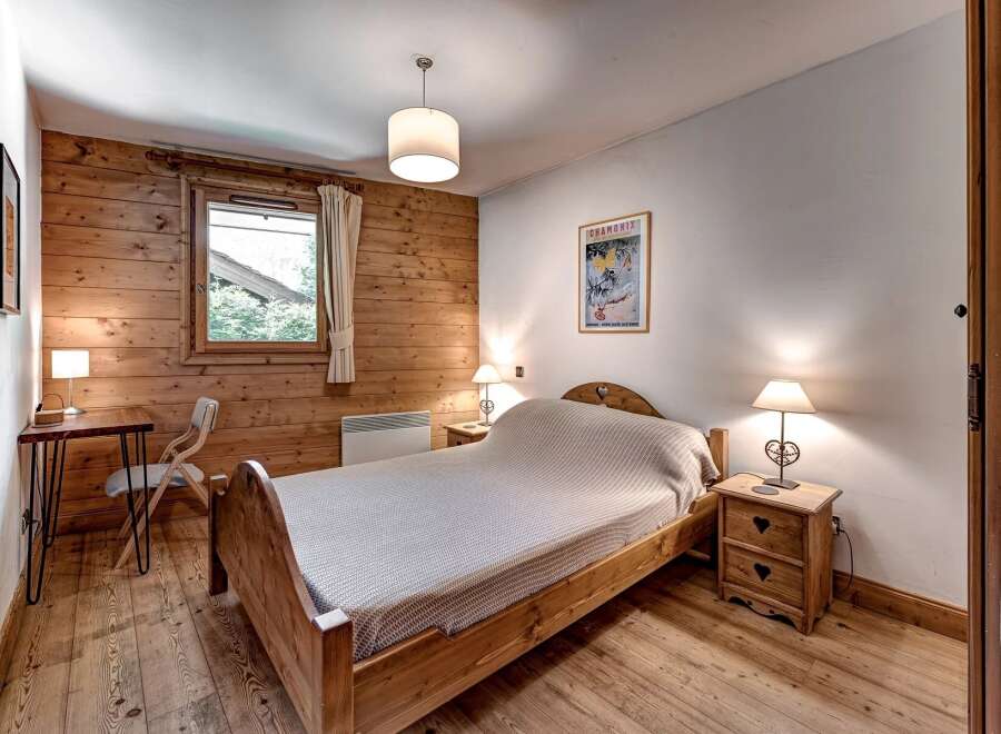 Experience rustic charm in this cozy bedroom featuring warm wood paneling and a comfortable wooden bed.