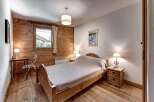 Experience rustic charm in this cozy bedroom featuring warm wood paneling and a comfortable wooden bed.