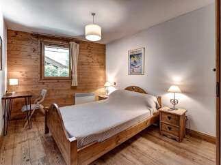 Experience rustic charm in this cozy bedroom featuring warm wood paneling and a comfortable wooden bed.