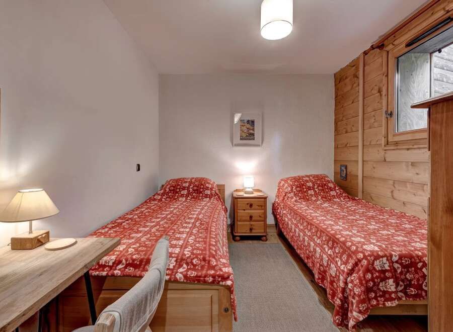 This charming bedroom features two twin beds, each adorned with a cozy red and white patterned comforter, perfect for a restful night's sleep.