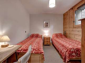 This charming bedroom features two twin beds, each adorned with a cozy red and white patterned comforter, perfect for a restful night's sleep.