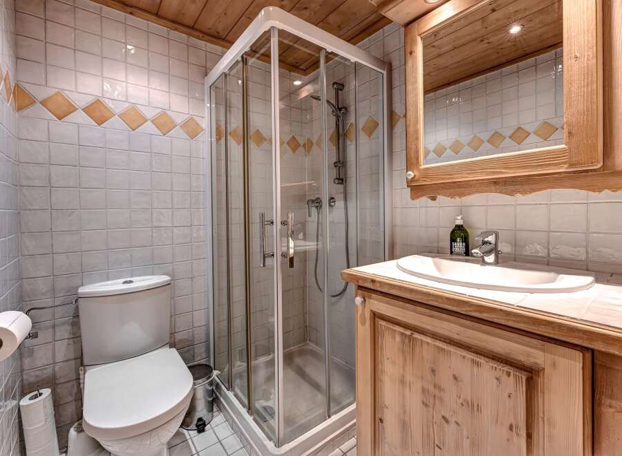 This charming bathroom features a modern glass-enclosed shower, a pristine white toilet, and a stylish vanity with a sink.