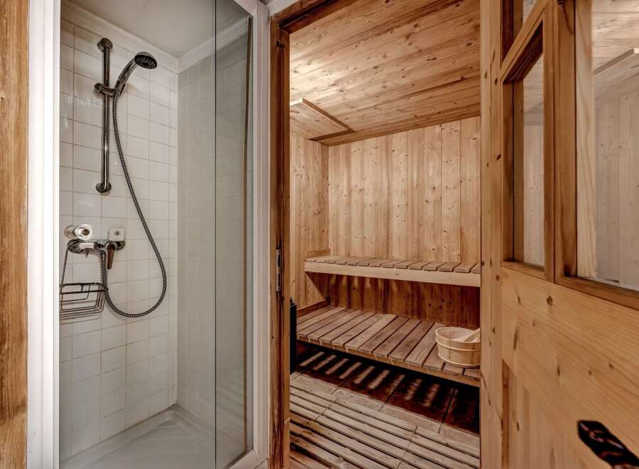 Experience ultimate relaxation in this luxurious spa-like bathroom featuring a private sauna with wooden benches and a separate shower area.
