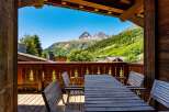 Enjoy breathtaking mountain views from this charming chalet's private balcony, complete with a rustic wooden table and chairs.