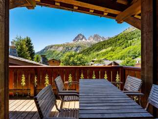 Enjoy breathtaking mountain views from this charming chalet's private balcony, complete with a rustic wooden table and chairs.