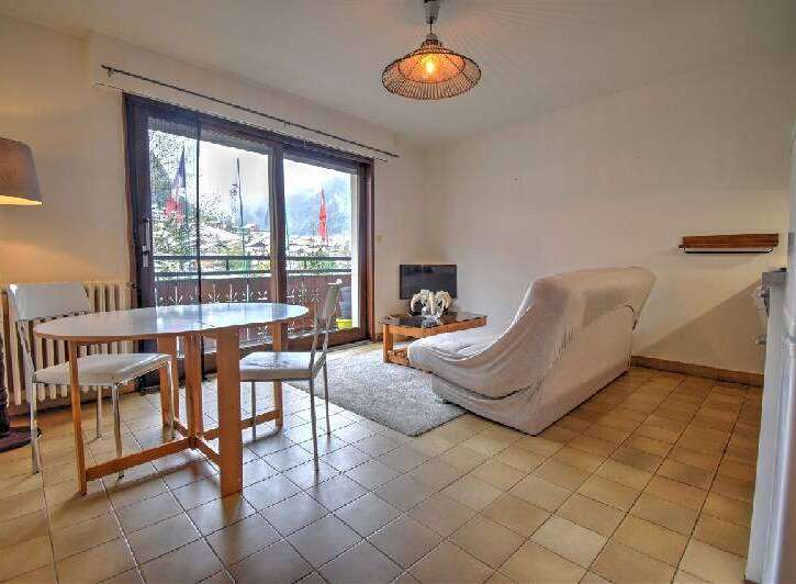 Enjoy stunning mountain views from this charming apartment, featuring a cozy living area with a sofa and coffee table, perfect for relaxing after a day of skiing.