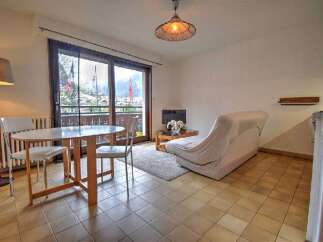 Enjoy stunning mountain views from this charming apartment, featuring a cozy living area with a sofa and coffee table, perfect for relaxing after a day of skiing.