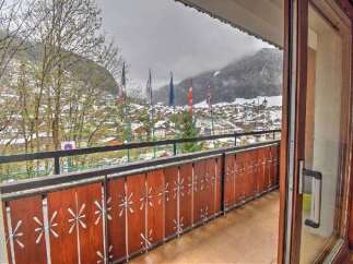 Enjoy breathtaking mountain views from this charming balcony overlooking a snow-dusted village.