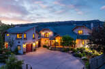 Experience luxury living in this stunning mountain home, featuring a grand entrance with a covered porch and inviting rocking chairs.