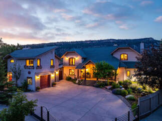 Experience luxury living in this stunning mountain home, featuring a grand entrance with a covered porch and inviting rocking chairs.