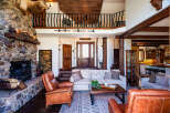 Experience rustic luxury in this stunning lodge-style living room, featuring a grand stone fireplace and exposed wooden beams.