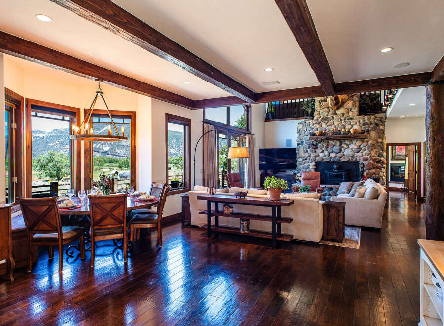 Experience rustic elegance in this stunning mountain home, featuring a spacious dining area with panoramic views and a grand living room centered around a magnificent stone fireplace.