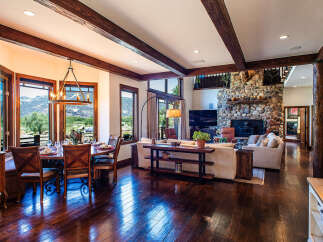 Experience rustic elegance in this stunning mountain home, featuring a spacious dining area with panoramic views and a grand living room centered around a magnificent stone fireplace.