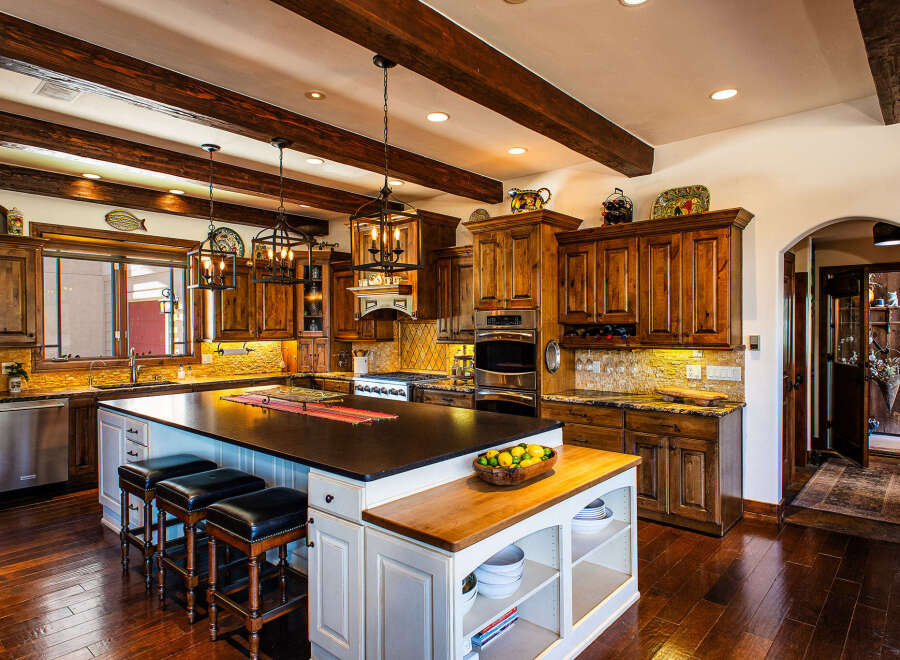 Experience luxury in this stunning kitchen, featuring rich wooden cabinetry, a spacious granite island with bar seating, and high-end stainless steel appliances.