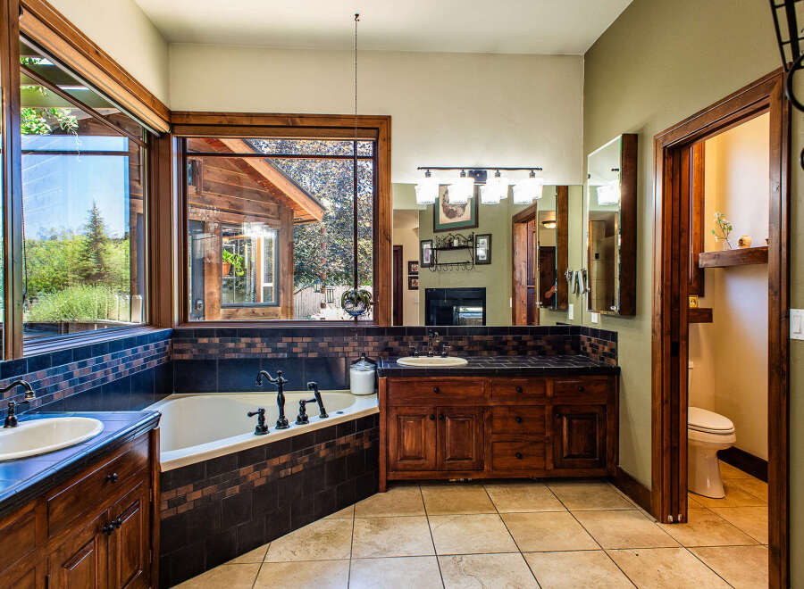 Experience luxury in this spacious bathroom featuring a deep soaking tub with a scenic view, complemented by a double vanity with ample counter space.
