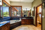 Experience luxury in this spacious bathroom featuring a deep soaking tub with a scenic view, complemented by a double vanity with ample counter space.