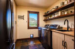 This laundry room boasts modern stainless steel appliances, including a washer and dryer, complemented by a sleek black sink and faucet.