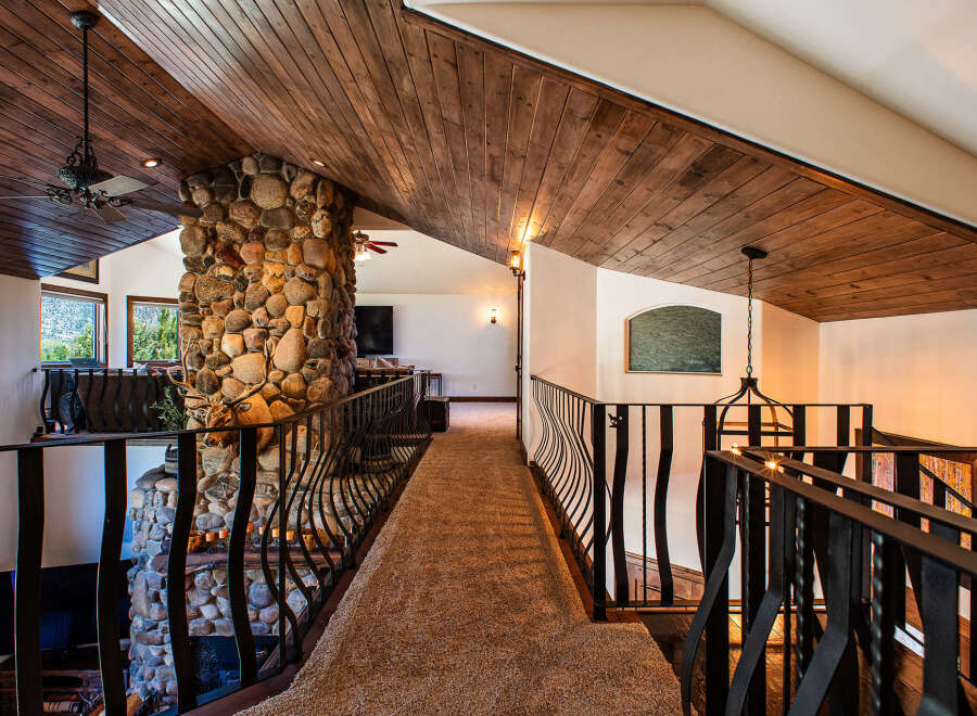 Experience rustic elegance in this stunning home featuring a grand stone fireplace and a beautifully wood-paneled vaulted ceiling.