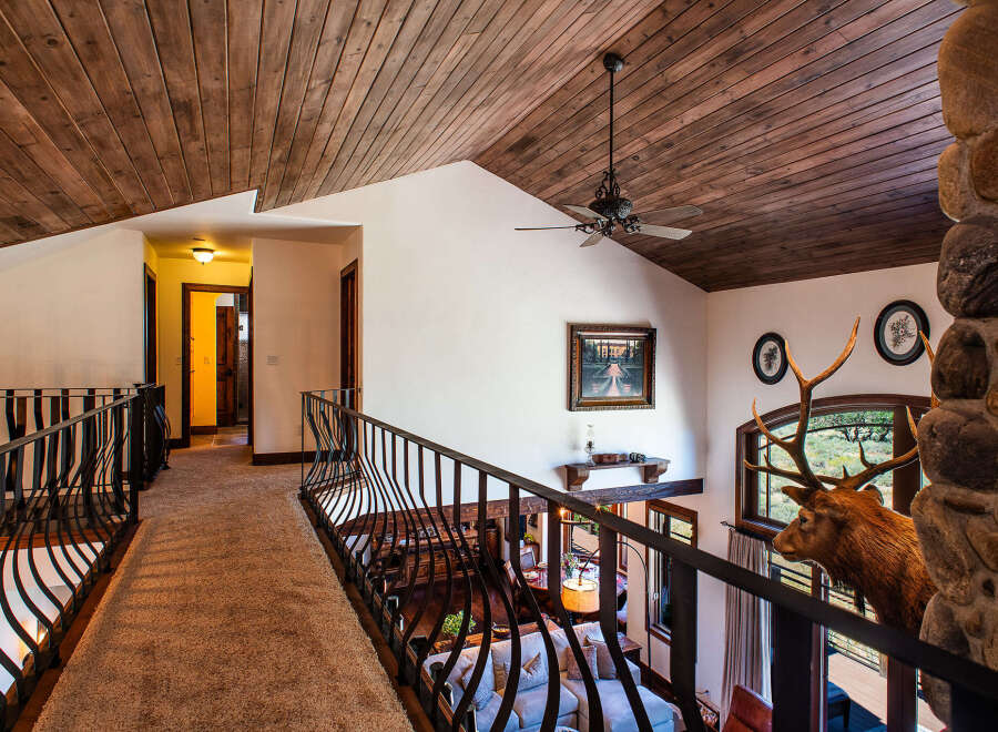Experience rustic elegance in this stunning home featuring a grand wooden-beamed ceiling and a unique stone fireplace.