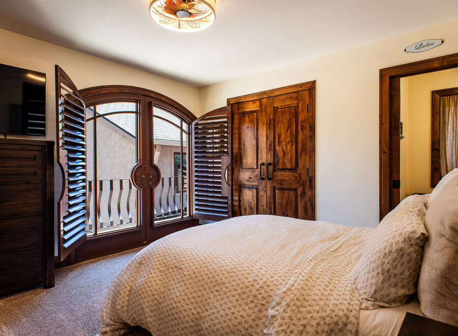 Experience rustic charm in this inviting bedroom, featuring elegant wooden shutters that open to a private balcony.