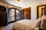 Experience rustic charm in this inviting bedroom, featuring elegant wooden shutters that open to a private balcony.