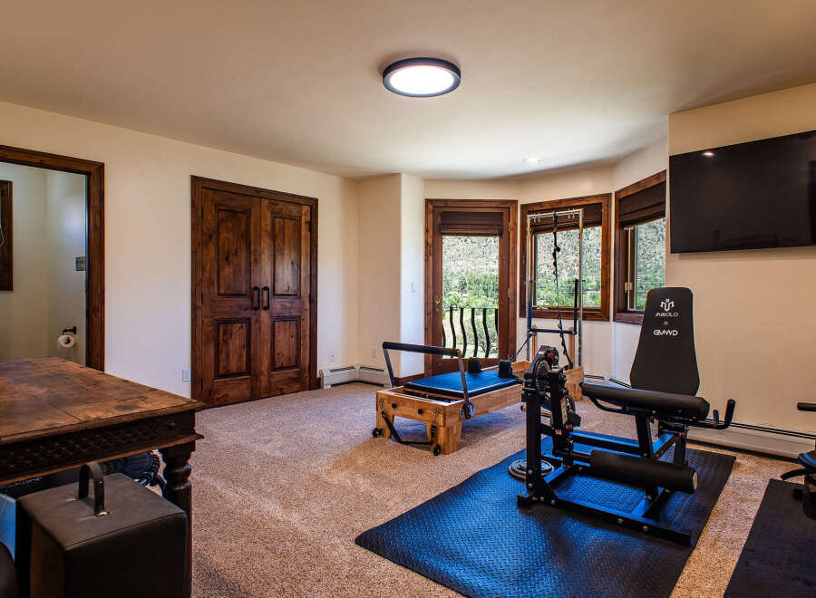 This home gym features a variety of exercise equipment, including a Pilates reformer and a weight machine, perfect for a full-body workout.