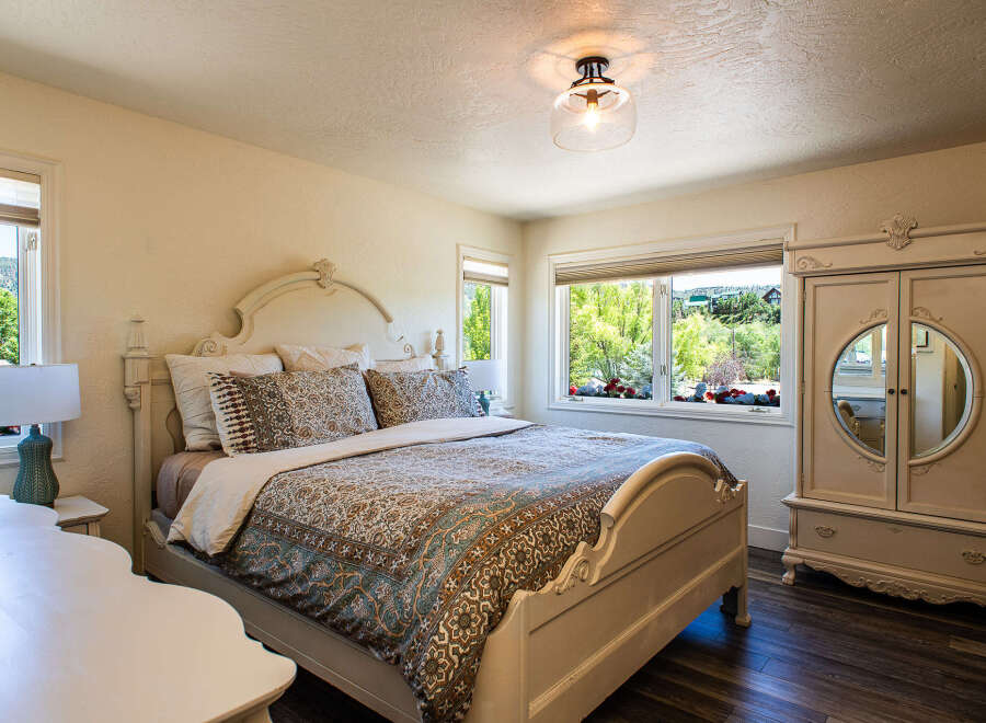 Experience serene living in this charming bedroom, featuring a beautifully appointed bed with a decorative headboard and a coordinating duvet.