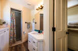 This charming bathroom features a vibrant floral shower curtain, a modern vanity with a vessel sink, and a spacious walk-in closet.