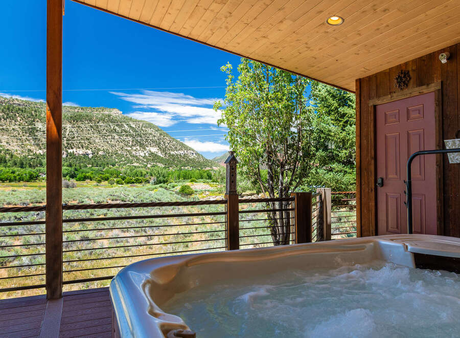 Experience ultimate relaxation with this stunning hot tub, offering breathtaking mountain views and a serene natural backdrop.