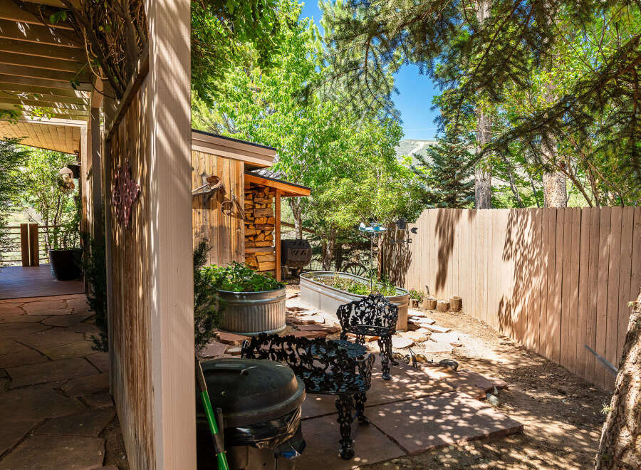 Enjoy outdoor living in this charming backyard featuring a rustic wooden fence and a covered patio area.